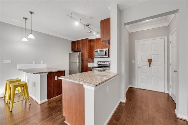 kitchen with stainless steel appliances, a kitchen breakfast bar, dark hardwood / wood-style flooring, decorative light fixtures, and kitchen peninsula