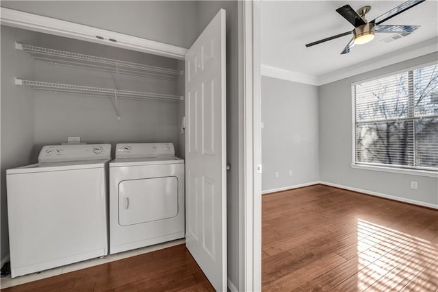 clothes washing area with dark wood-type flooring, ceiling fan, crown molding, and washer and clothes dryer