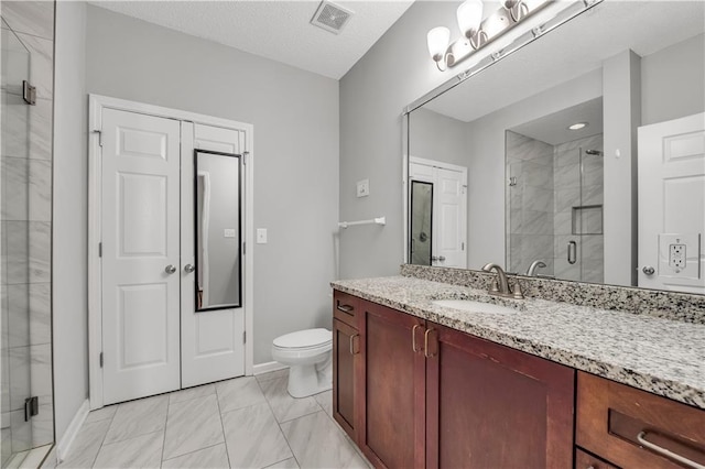 bathroom with vanity, a shower with shower door, and toilet