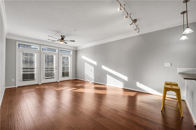 unfurnished living room with crown molding, ceiling fan, dark hardwood / wood-style floors, track lighting, and a textured ceiling