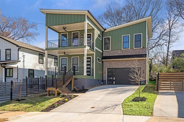 view of front of property featuring board and batten siding, concrete driveway, a balcony, and fence