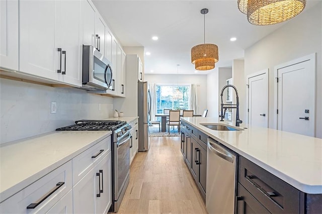 kitchen with white cabinets, light wood-style flooring, appliances with stainless steel finishes, and a sink