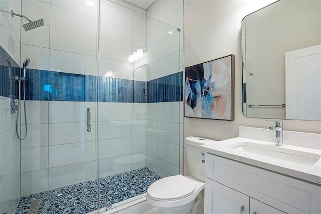 bathroom with vanity, a shower stall, and toilet