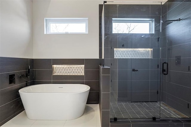 full bathroom with a shower stall, tile walls, wainscoting, and a freestanding bath