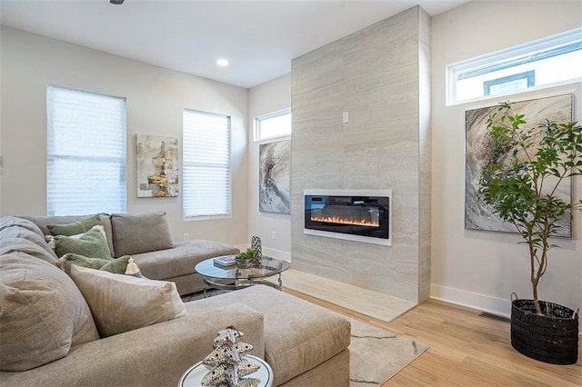 living area featuring recessed lighting, light wood-style flooring, a fireplace, and baseboards