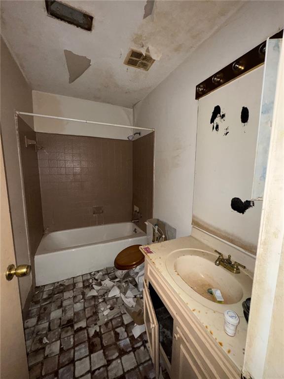 full bathroom with tiled shower / bath combo, vanity, and toilet