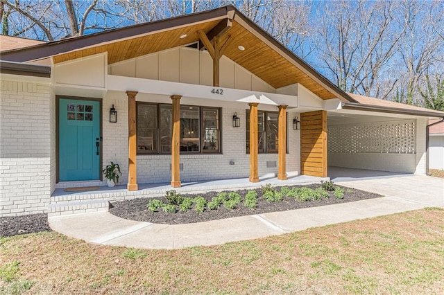 view of front of house featuring brick siding, covered porch, a carport, concrete driveway, and board and batten siding