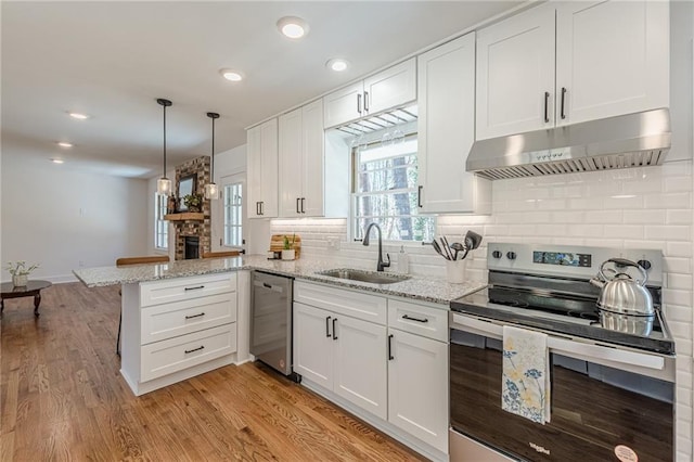 kitchen featuring under cabinet range hood, a sink, white cabinetry, appliances with stainless steel finishes, and a peninsula