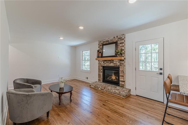 living area with recessed lighting, a brick fireplace, baseboards, and wood finished floors