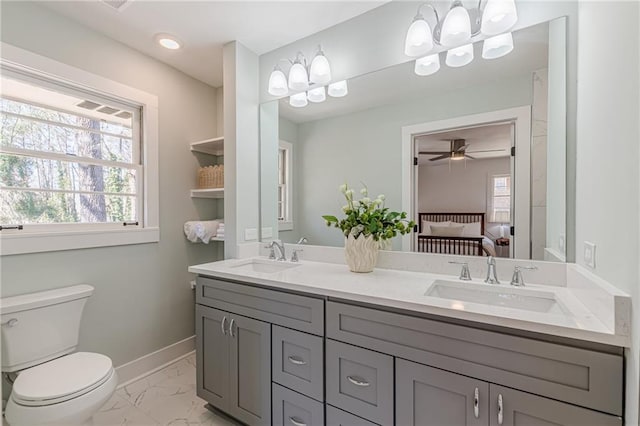 ensuite bathroom with a healthy amount of sunlight, marble finish floor, and a sink