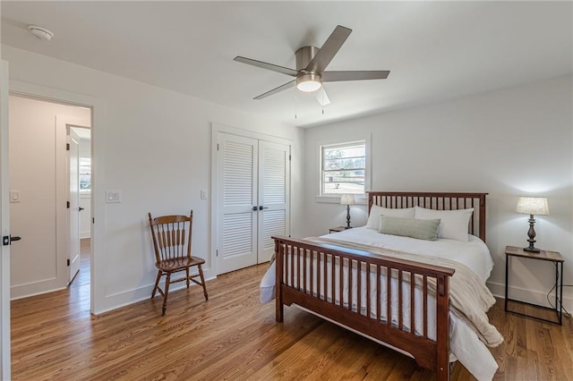 bedroom featuring a ceiling fan, wood finished floors, a closet, and baseboards