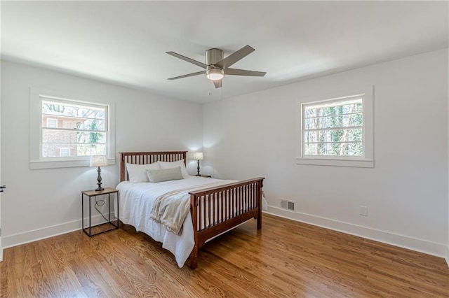 bedroom with visible vents, baseboards, light wood-style flooring, and a ceiling fan