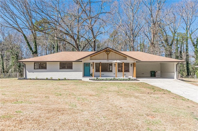 ranch-style home with an attached carport, fence, a front lawn, concrete driveway, and brick siding