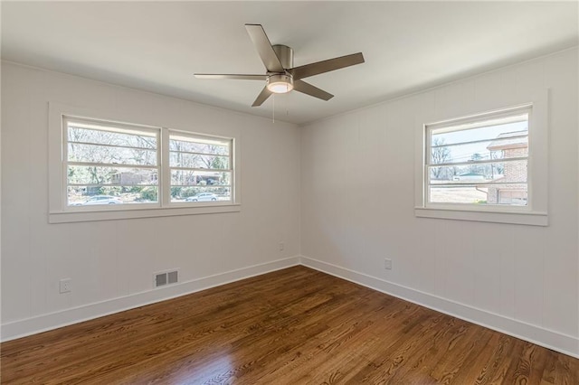 spare room with visible vents, plenty of natural light, dark wood-style floors, and a ceiling fan