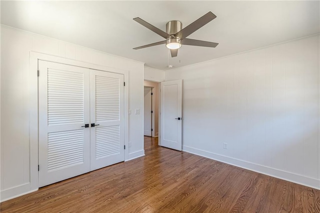 unfurnished bedroom with a closet, baseboards, wood finished floors, and a ceiling fan