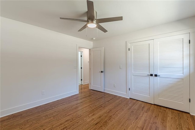 unfurnished bedroom with a closet, baseboards, wood finished floors, and a ceiling fan