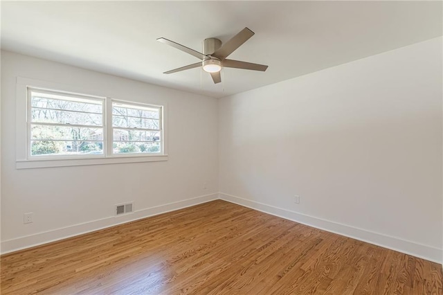 unfurnished room with visible vents, light wood-style flooring, a ceiling fan, and baseboards