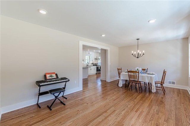 dining space with visible vents, an inviting chandelier, baseboards, and light wood-style floors