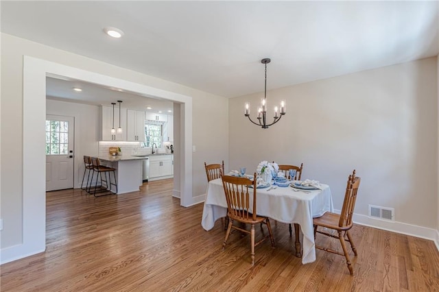 dining area featuring visible vents, an inviting chandelier, baseboards, and light wood-style floors