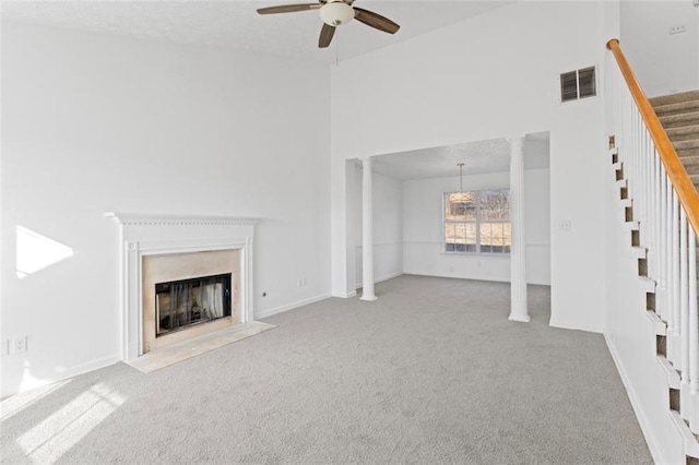 unfurnished living room with a high ceiling, light colored carpet, ceiling fan, and ornate columns