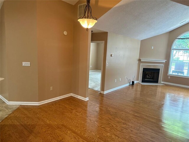 2191 Rockbridge Rd Unit 2603, Stone Mountain, GA 30087 - unfurnished living room with wood finished floors, a textured ceiling, vaulted ceiling, and a tile fireplace