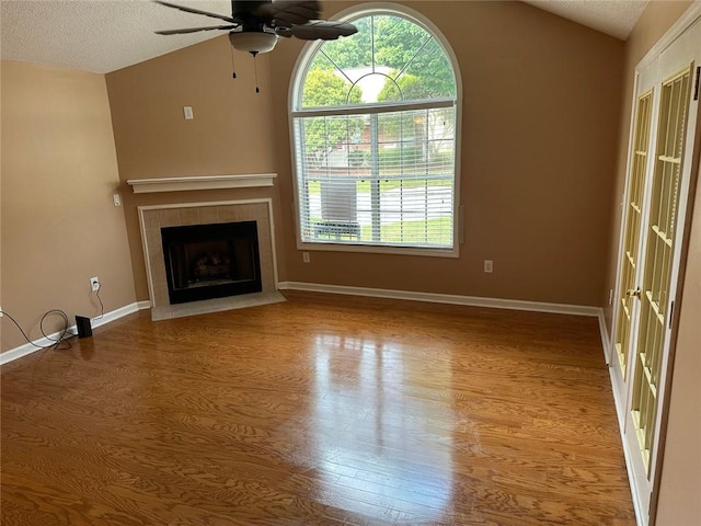 2191 Rockbridge Rd Unit 2603, Stone Mountain, GA 30087 - unfurnished living room with lofted ceiling, wood finished floors, a ceiling fan, a tiled fireplace, and a textured ceiling