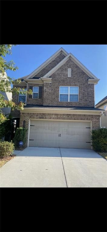 view of front of house featuring an attached garage, concrete driveway, and brick siding