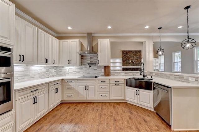 kitchen with a sink, light countertops, wall chimney exhaust hood, stainless steel appliances, and tasteful backsplash