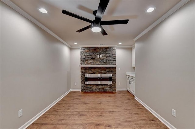 unfurnished living room featuring crown molding, a stone fireplace, ceiling fan, recessed lighting, and light wood finished floors