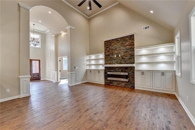 unfurnished living room with visible vents, wood finished floors, a fireplace, high vaulted ceiling, and a ceiling fan