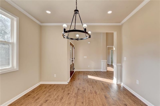 unfurnished dining area with baseboards, ornamental molding, wood finished floors, and a chandelier