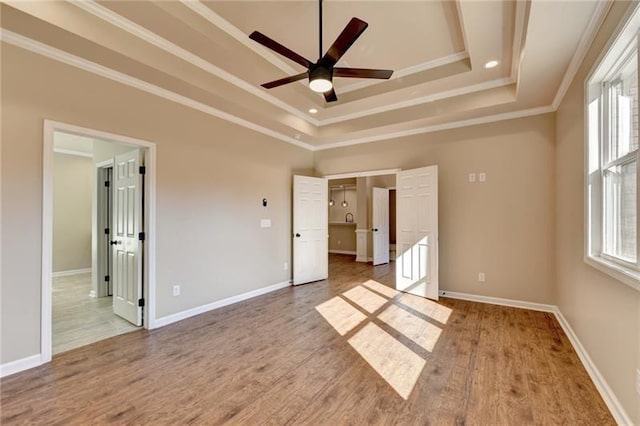 unfurnished bedroom with crown molding, a raised ceiling, and wood finished floors