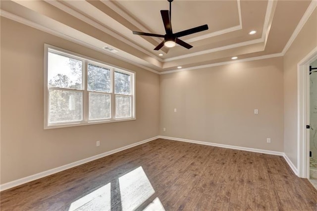spare room featuring a ceiling fan, crown molding, wood finished floors, a tray ceiling, and recessed lighting