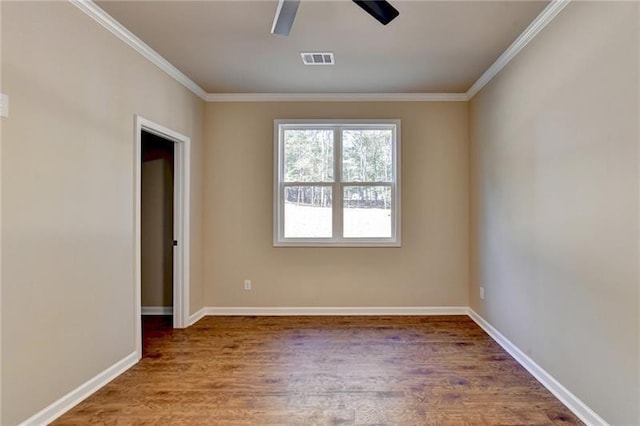 empty room featuring crown molding, ceiling fan, visible vents, and wood finished floors