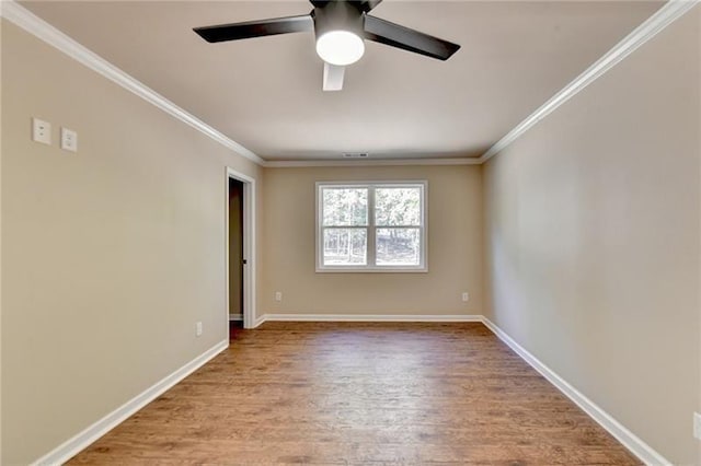 spare room featuring baseboards, ornamental molding, ceiling fan, and wood finished floors