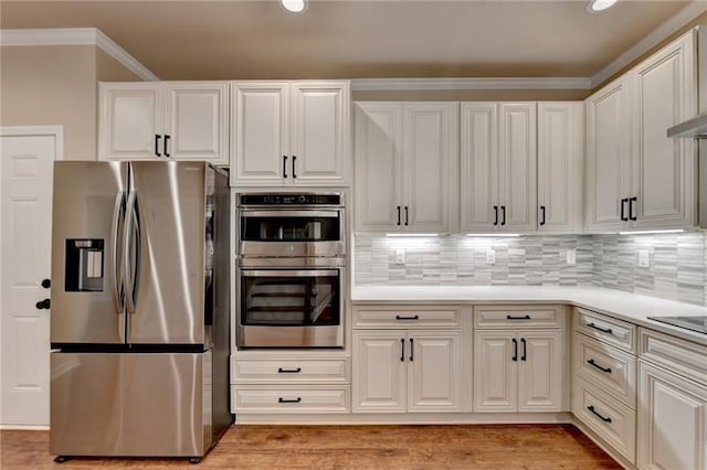 kitchen featuring crown molding, light countertops, white cabinetry, and stainless steel appliances
