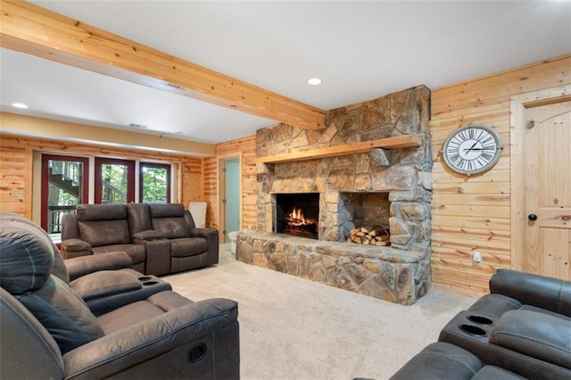 living room with beamed ceiling, wooden walls, carpet flooring, and a stone fireplace