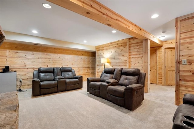 carpeted home theater room with beamed ceiling and wooden walls