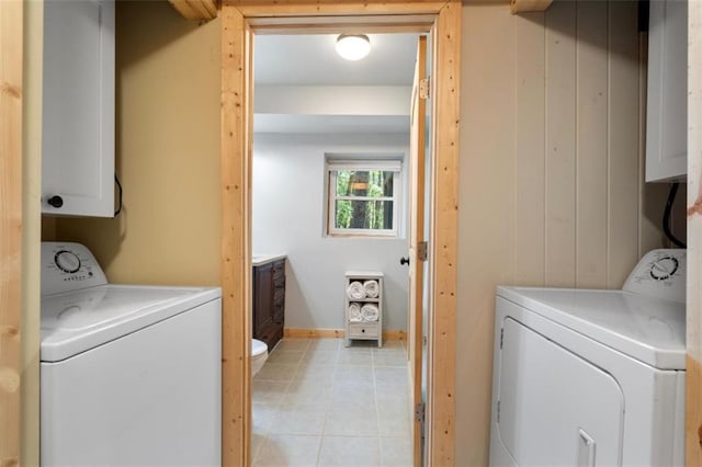 laundry room with cabinets, washing machine and dryer, light tile patterned floors, and wood walls