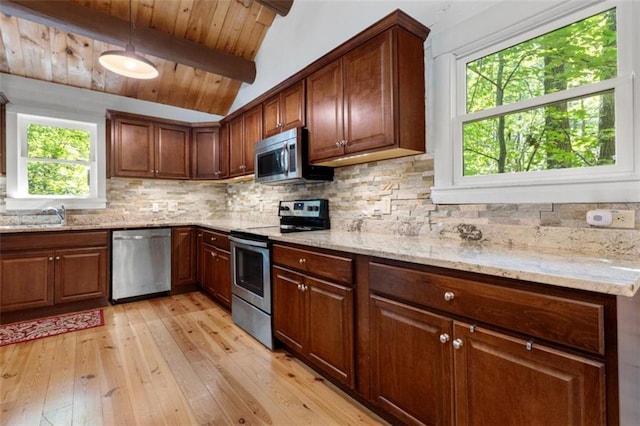 kitchen featuring stainless steel appliances, light stone countertops, sink, and backsplash