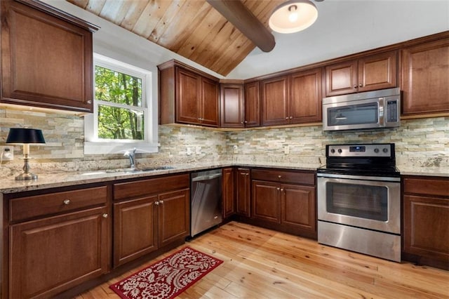 kitchen with light stone countertops, appliances with stainless steel finishes, sink, and light hardwood / wood-style floors