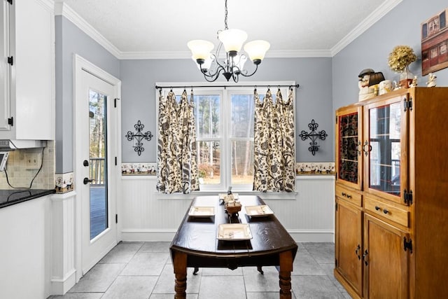 tiled dining area with ornamental molding, a healthy amount of sunlight, and a notable chandelier