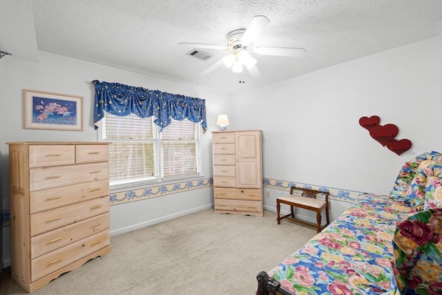 bedroom featuring ceiling fan, light carpet, and a textured ceiling