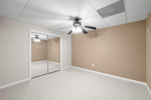 unfurnished bedroom with ceiling fan, a paneled ceiling, a closet, and carpet