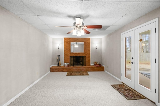 carpeted living room featuring french doors, a paneled ceiling, a fireplace, and ceiling fan