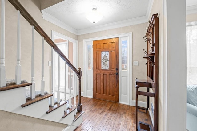 foyer featuring hardwood / wood-style flooring, ornamental molding, and a textured ceiling