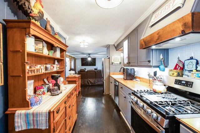 kitchen with dark wood-style flooring, light countertops, decorative backsplash, appliances with stainless steel finishes, and ceiling fan