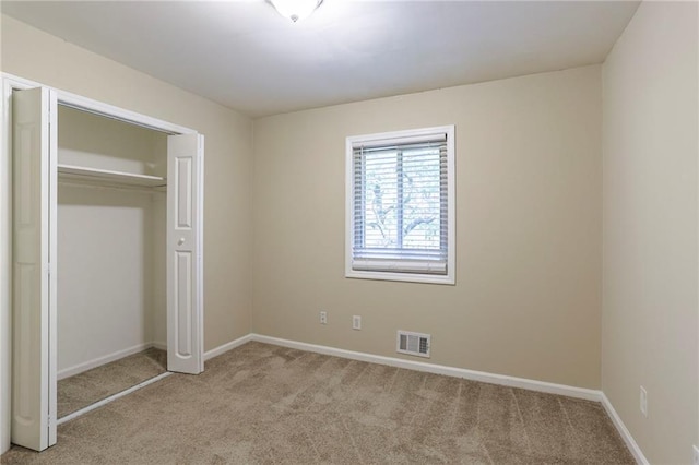 unfurnished bedroom featuring light carpet and a closet