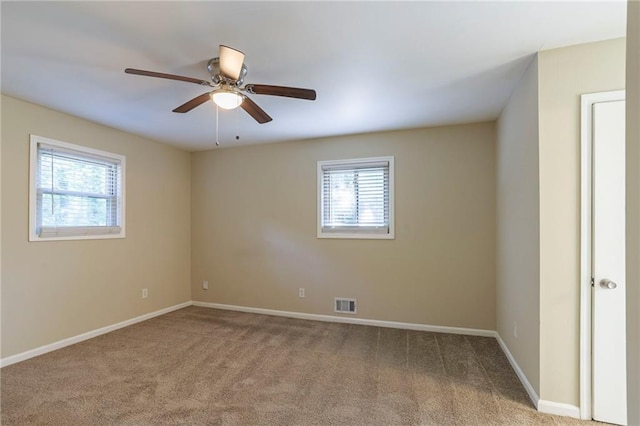 spare room with ceiling fan, light colored carpet, and plenty of natural light