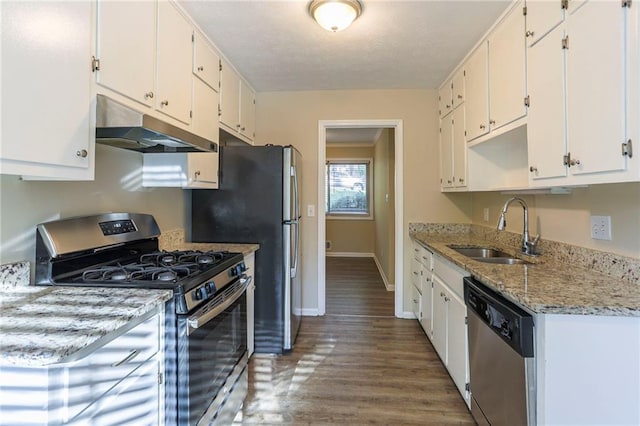 kitchen with dark wood-type flooring, sink, white cabinets, appliances with stainless steel finishes, and light stone countertops